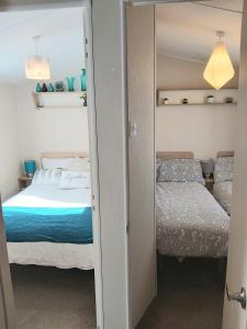 1 dormitorio con 2 camas y espejo en Griffiths, Seaview Caravan Park, Whitstable en Kent