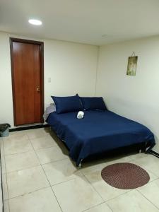 a blue bed in a room with a door at Hospedaje Room's El Dorado in Bogotá