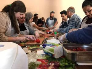 a group of people standing around a table preparing food at Safi Kitchen Hostel in Aş Şāfī