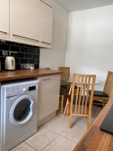 a kitchen with a washing machine and a table at Cosy 2 Bed Flat 1 in Swansea - Home away from Home in Swansea