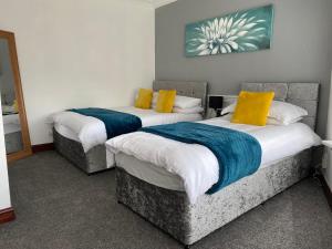 two beds in a room with yellow and blue pillows at Cosy 2 Bed Flat 1 in Swansea - Home away from Home in Swansea