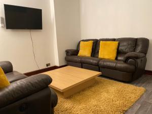 a living room with a leather couch and a coffee table at Cosy 2 Bed Flat 1 in Swansea - Home away from Home in Swansea