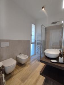 uma casa de banho com 2 lavatórios brancos e uma banheira em La Rondinella Apartments em Bardolino
