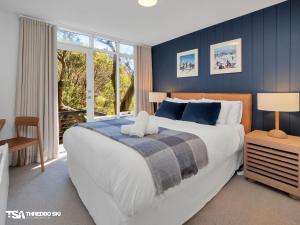 a bedroom with a large bed with blue walls at Stepping Stone in Thredbo