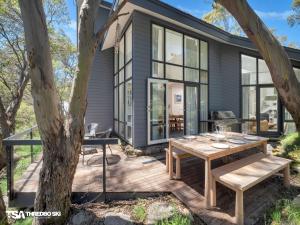 a house with a wooden deck with a table at Stepping Stone in Thredbo