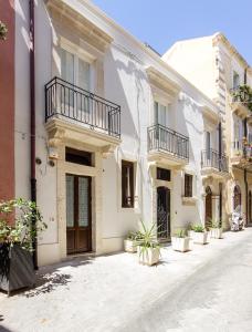 a row of white buildings with potted plants on a street at Appartamento a Ortigia in Syracuse