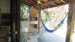 a hammock on a patio with a table and chairs at Chalé Recanto do Barão in Boicucanga