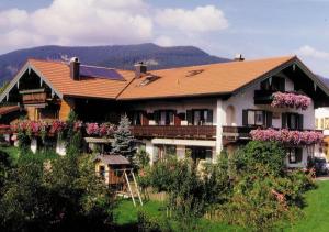 a large house with a red roof and flowers at Haus Gehmacher-Maier - Chiemgau Karte in Inzell