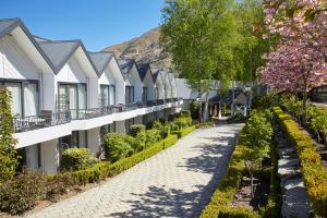 a row of houses with a pathway and trees at Nugget Point Hotel in Queenstown