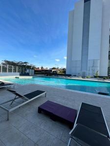a swimming pool with two lounge chairs next to a building at Bambu-Rivera Club Residences in San José