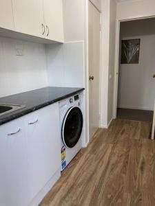 a kitchen with a washing machine in a white kitchen at Valley House - Location Location Location - Comfortable home in the heart of Healesville in Healesville