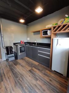 a kitchen with a white refrigerator and wooden floors at Container ABOBORA na natureza da Serra Gaúcha in Flores da Cunha