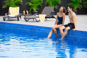 a man and woman sitting on the edge of a swimming pool at voco Orchard Singapore in Singapore