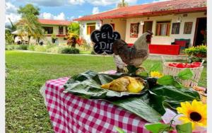 a chicken sitting on a table with a plate of food at FINCA HOTEL EL LAUREL - Parque del Café in Montenegro
