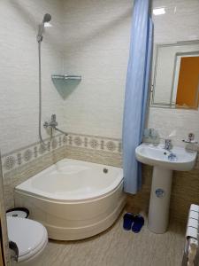 La salle de bains est pourvue d'une baignoire, de toilettes et d'un lavabo. dans l'établissement OQSAROY SAMARKAND Guest House, à Samarcande