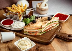 a sandwich on a cutting board with fries and sauce at Hotel Mumbai House-LIG Behind CHL Hospital in Indore