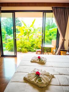 a bedroom with two beds and a large window at Bannsuan Amaleena in Ko Yao Noi