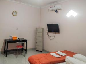 a bedroom with a bed and a desk and a television at RedDoorz @ Makarios Hotel Poso in Poso