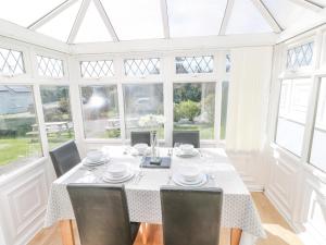 a dining room with a table and chairs and windows at Grooms Cottage in Tenby