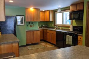 a kitchen with wooden cabinets and a black appliances at Whole home, private lake, sauna, WFH office in Michigamme