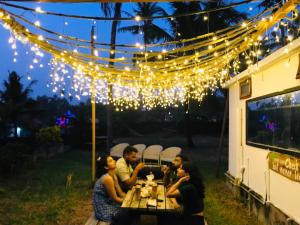 Un grupo de personas sentadas en una mesa bajo luces. en Vibes Beach House, en Varkala