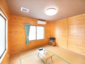 Tabist Hamatoya Ryokan Mens Only في Sodegaura: غرفة بجدران خشبية وطاولة ونافذة