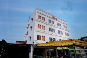 un bâtiment blanc avec des fenêtres orange à côté d'un magasin dans l'établissement OYO 622 Bakti Homestay, à Medan