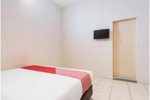 - une chambre avec un lit et une télévision murale dans l'établissement OYO 622 Bakti Homestay, à Medan