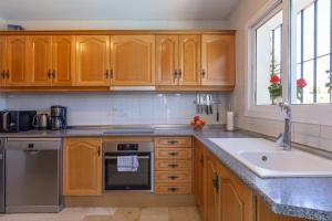 kuchnia z drewnianymi szafkami i zlewem w obiekcie Super Villa priv heated pool 3bed w mieście La Cala de Mijas