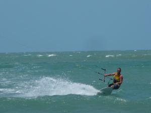 un hombre está en una tabla de surf en el océano en Pousada Lacula, en Praia de Moitas