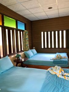 two beds in a room with windows on a boat at Pop riverside trat in Trat
