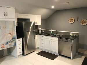 a kitchen with a stainless steel refrigerator and white cabinets at Lake and Bridge View Vacation Home in West Kelowna