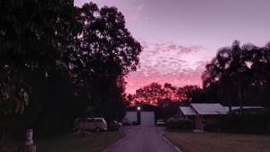 einen Sonnenuntergang über einer Straße mit einem Haus und Bäumen in der Unterkunft Tukawyl Retreat Landsborough in Landsborough