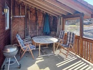 een tafel en stoelen op een veranda van een hut bij Four-Bedroom Holiday home in Sirevåg in Sirevåg