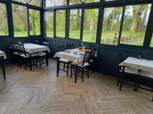 a dining room with tables and chairs and windows at Chambres d'hôtes Le Petit Roche in Arc-et-Senans