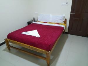 a bed with a red blanket on top of it at jack N jill holidays inn in Ooty