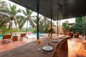 a table with glasses of orange juice and a pool at Bella Canis the Pvt Pool & Lawn at StayVista in Anjuna