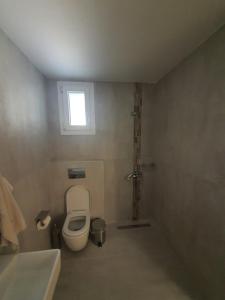 a small bathroom with a toilet and a window at New apartment ,50m from the sea at Nea Irakleia. in Nea Irakleia