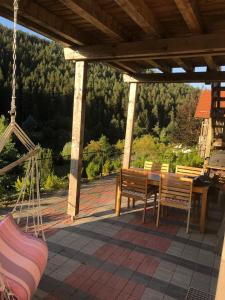 eine Veranda mit einem Holztisch, Stühlen und einer Schaukel in der Unterkunft Ferienwohnung am Badesee mit priv. Sauna /Terrasse in Erzgrube