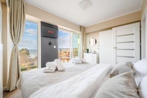 a bedroom with a large white bed with a large window at Laurasapartment in Jarosławiec