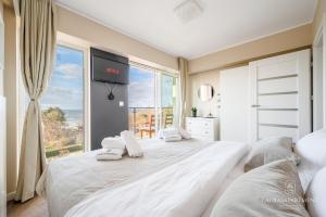 a bedroom with a large white bed with a large window at Laurasapartment in Jarosławiec +26 photos