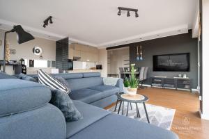 a living room with a blue couch and a kitchen at Laurasapartment in Jarosławiec