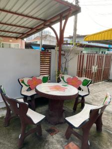 a table and two chairs and a table with flowers on it at Pani House Hatyai 1 in Hat Yai