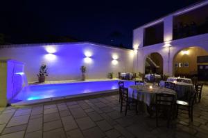 a patio with tables and a swimming pool at night at Agriturismo Masseria Santa Lucia al Bradano in Matera