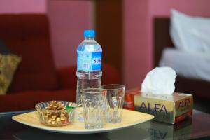 a bottle of water and glasses on a table at FAAZ Residency in Kozhikode