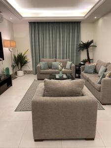 Sala de estar con 2 sofás y mesa en Alarjan Dream, en Riad
