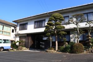 出雲市にある出雲大社　御師の宿　ますや旅館の木の立つ建物の前に停まるバス