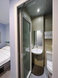 uma casa de banho com um lavatório, um WC e uma cama em Fragrance Hotel - Lavender em Singapura
