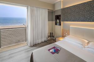 リド・ディ・イエゾロにあるHotel Rosanna 3 Stelle Superiorのベッドと大きな窓が備わるホテルルームです。