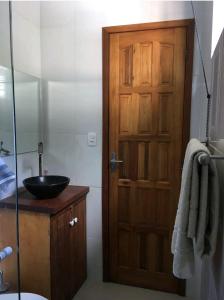a bathroom with a wooden door and a sink at Ohana suíte Abraão - Ilha Grande in Abraão